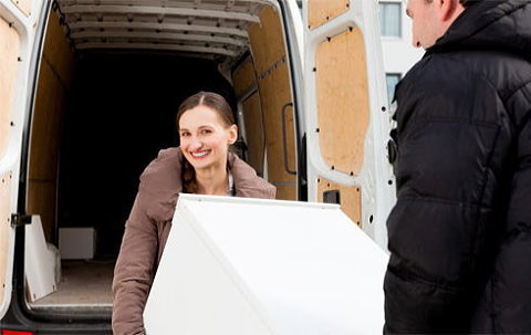 冷蔵庫を余裕の笑顔でトラックに積み込む女性